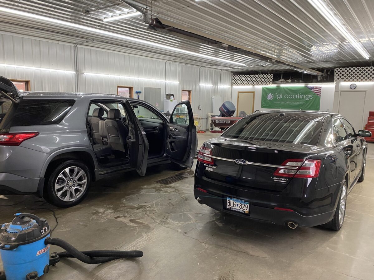 View of the Dirty Details Shop full of two autos and a boat. All are being worked on.